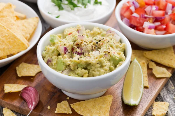 Guacamole, tomatová salsa a kukuřičnými chipsy na stole — Stock fotografie