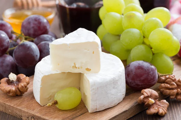 Fresh camembert on a wooden board and grapes — Stock Photo, Image