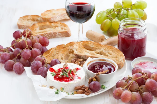Закуски для вина - камамбер с ягодным джемом, тостами и фруктами — стоковое фото