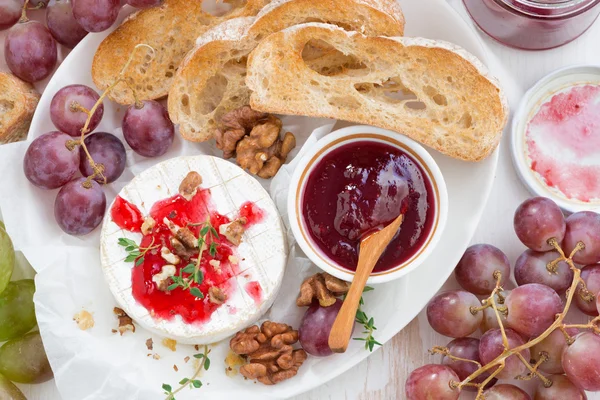 Hapjes voor wijn - camembert met berry jam, toast en vruchten — Stockfoto