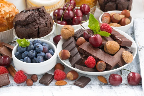 Sortimento de chocolate, bagas e nozes na mesa branca — Fotografia de Stock