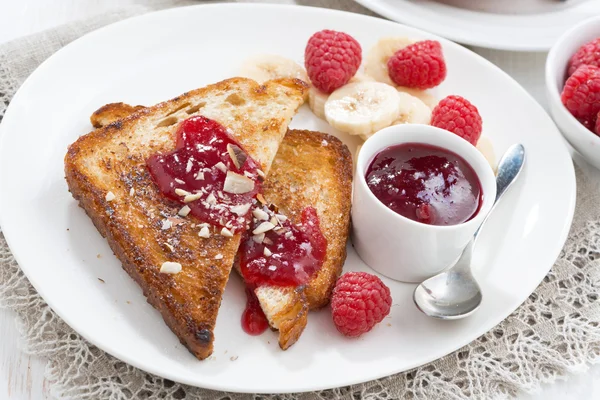 Sweet breakfast - toasts with raspberries, banana and jam — Stock Photo, Image