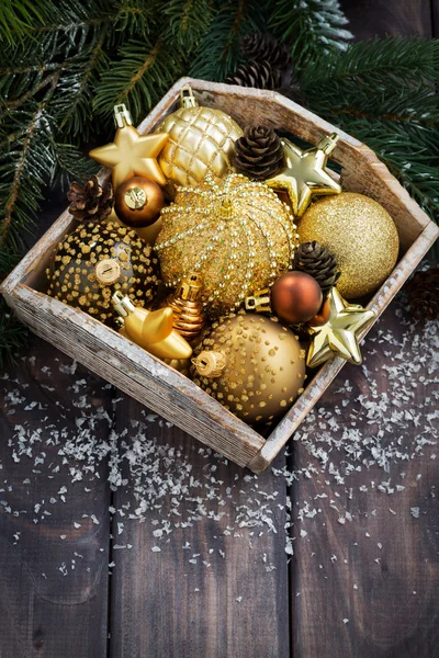 Boîte en bois avec décorations de Noël dorées sur la table, verticale — Photo