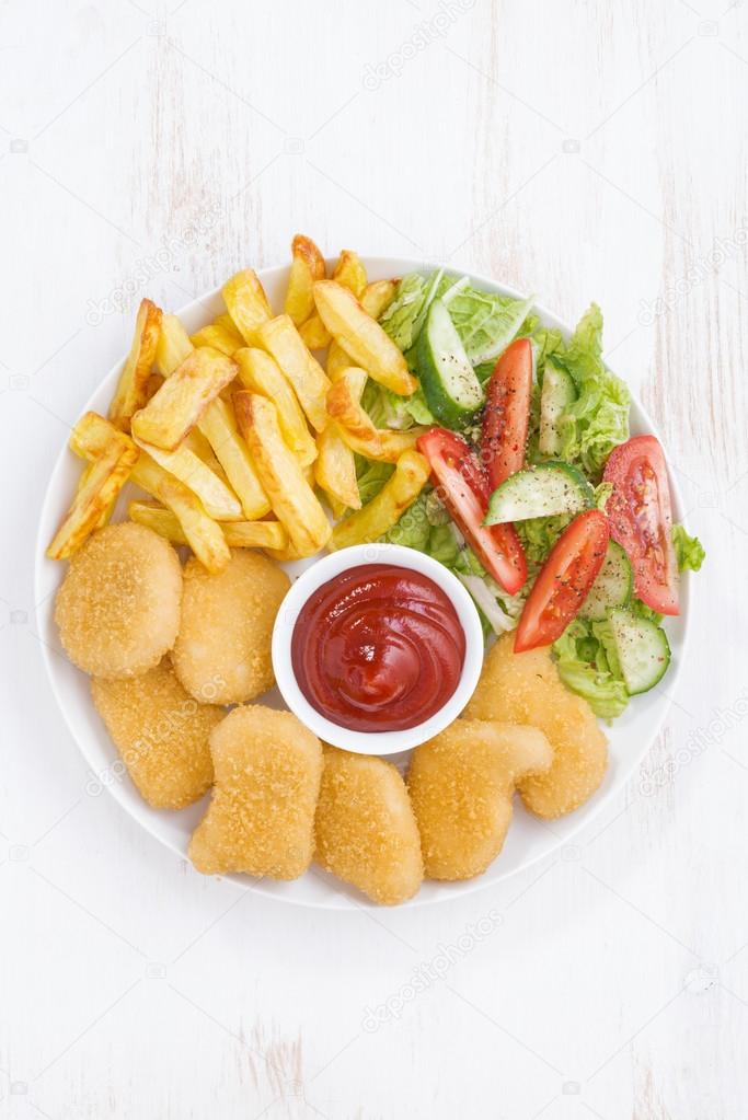 chicken nuggets, french fries and vegetable salad, vertical