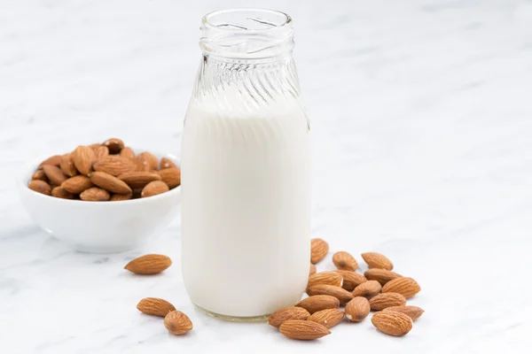 Lait d'amande dans une bouteille en verre sur table blanche, gros plan — Photo