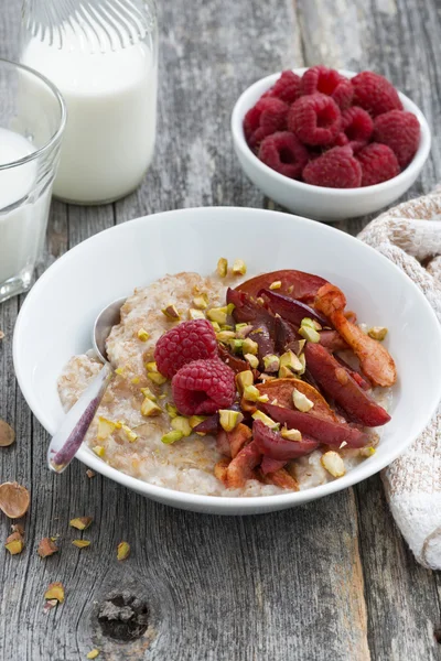 Oatmeal with baked fruit and pistachios for breakfast, vertical — Stock Photo, Image