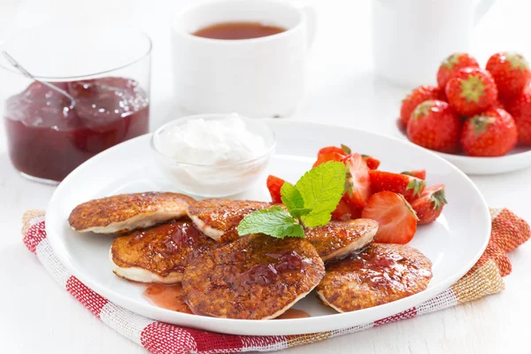Pancakes with fresh strawberries on a plate, jam and tea. — Stock Photo, Image