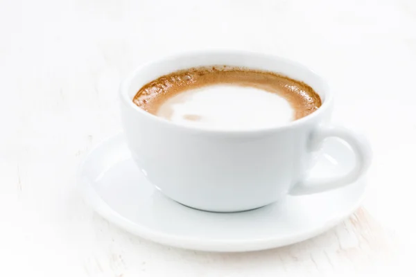 Šálek cappuccino na bílý dřevěný stůl, selektivní zaměření — Stock fotografie