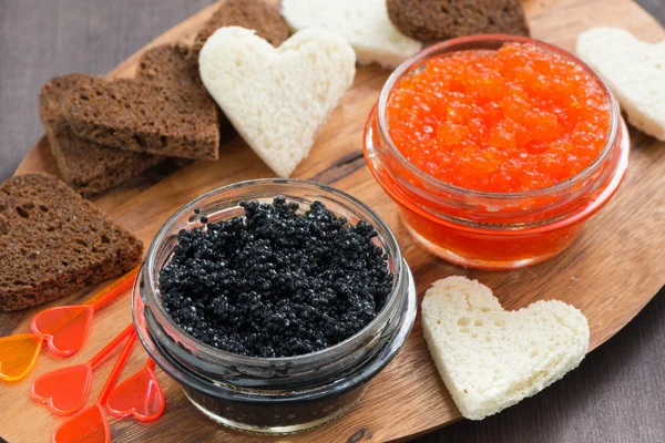 Festlig förrätt - skålar, röd och svart kaviar på träskiva — Stockfoto