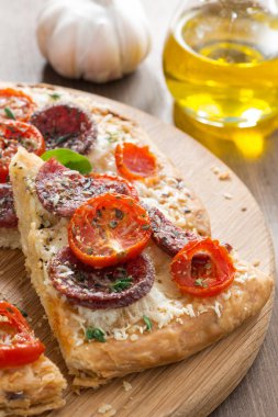 parça pizza salam ve ahşap tahta üzerinde domates ile