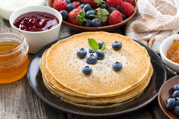 Crepes, fresh berries and jam on a wooden background, close-up — Stock Photo, Image