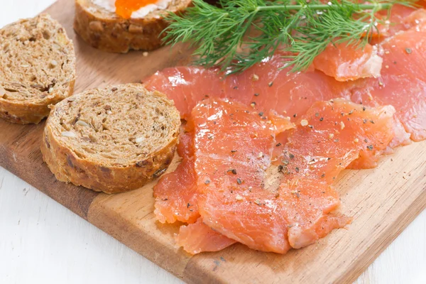 Appetizers - salted salmon, red caviar, toast on wooden board — Stock Photo, Image