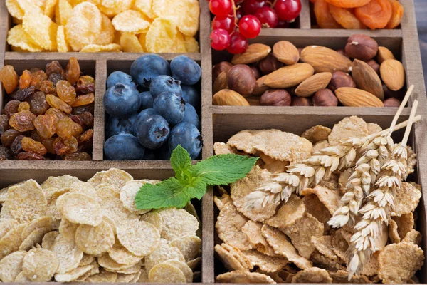 Snídaňové cereálie, sušené ovoce, plody a ořechy v dřevěné krabici — Stock fotografie