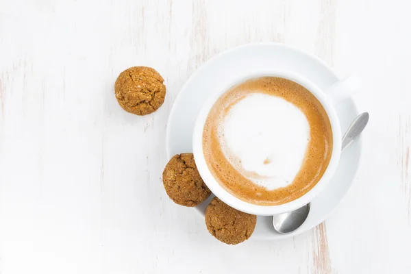 Šálek cappuccino a příchutí sušenky na bílý dřevěný stůl — Stock fotografie