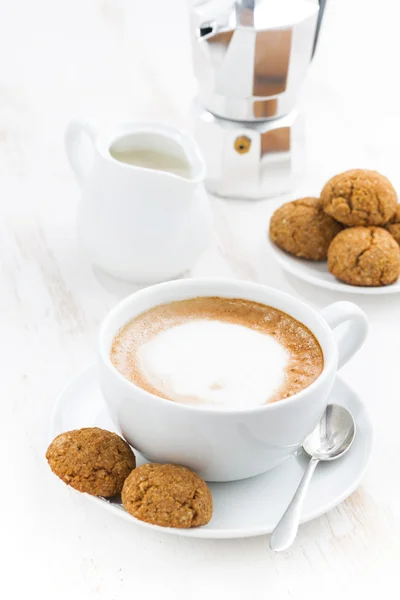 Kopje cappuccino en bitterkoekjes op witte tafel, verticale — Stockfoto