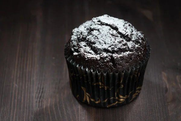 Magdalenas de chocolate con azúcar en polvo sobre un fondo oscuro —  Fotos de Stock