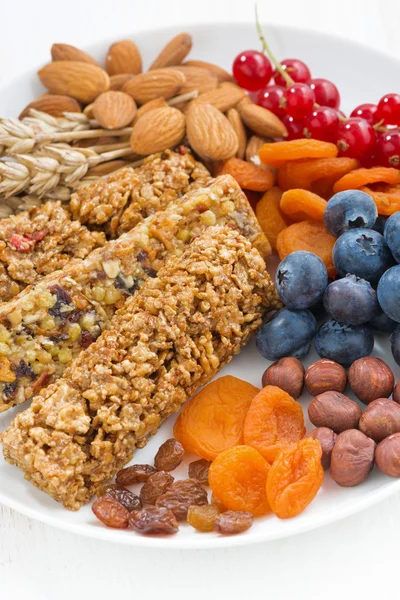 Barras de cereales muesli, fruta fresca y seca en un plato, primer plano — Foto de Stock