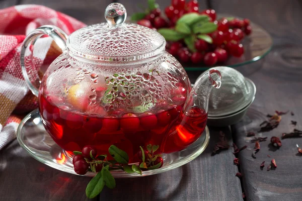 Té de bayas en tetera de vidrio sobre mesa de madera oscura —  Fotos de Stock