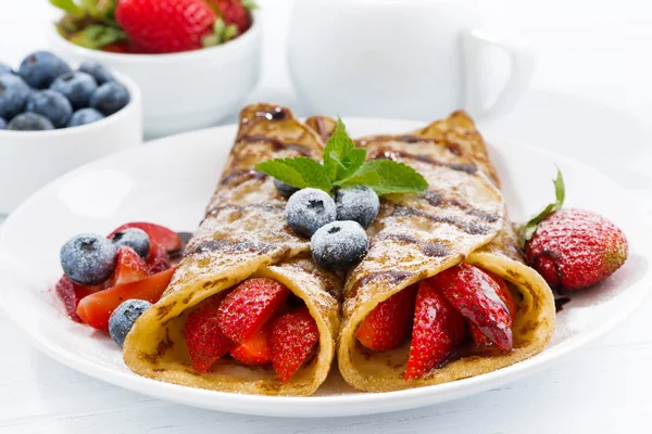 Crepes with berries and chocolate sauce for breakfast on plate — Stock Photo, Image