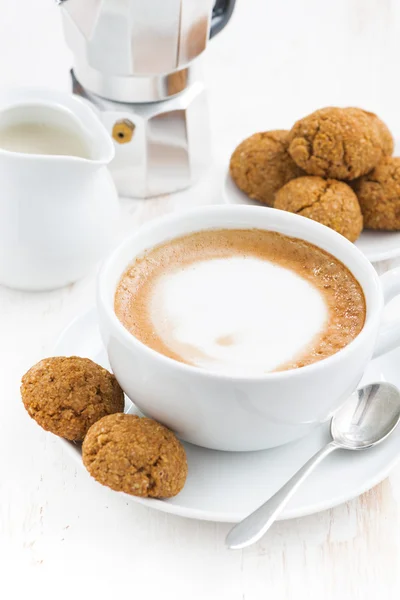 Kopp cappuccino och mandelbiskvier på vita träbord, närbild — Stockfoto