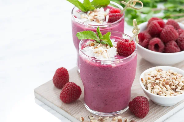 Batidos de bayas frescas con frutos secos en la pizarra blanca, primer plano —  Fotos de Stock