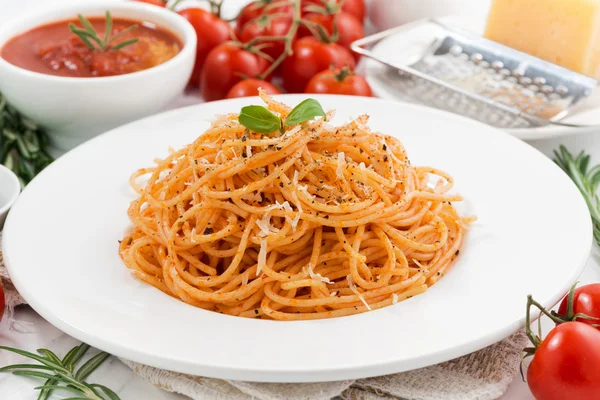 Pâtes avec sauce tomate sur une assiette et ingrédients, gros plan — Photo