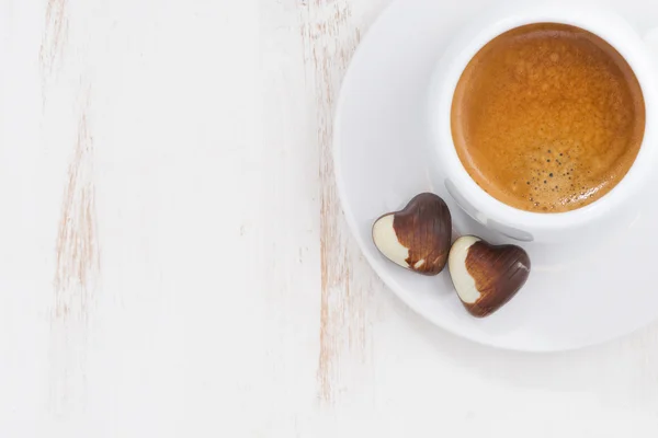 Çikolata kalpleri ve espresso beyaz arka planda, üstten görünüm — Stok fotoğraf