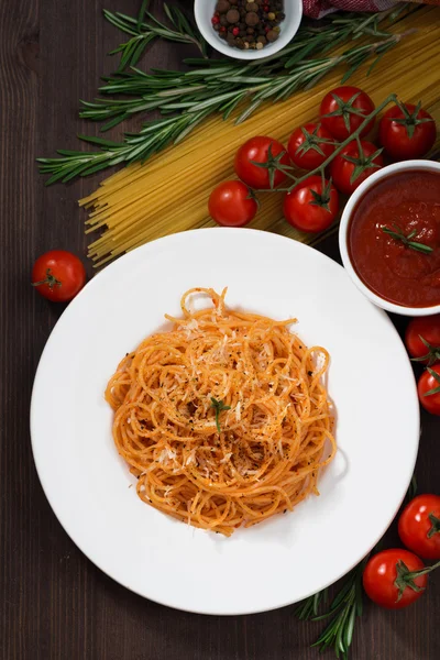 Spaghetti with tomato sauce and ingredients on a wooden table — Stock Photo, Image