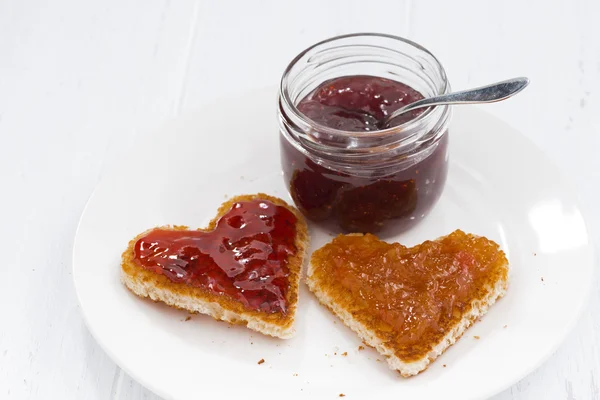 Two toasts in heart shape with fruit jams on plate — Stock Photo, Image