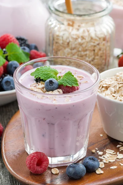 Batido de bayas con avena en un vaso sobre mesa de madera, vertical — Foto de Stock