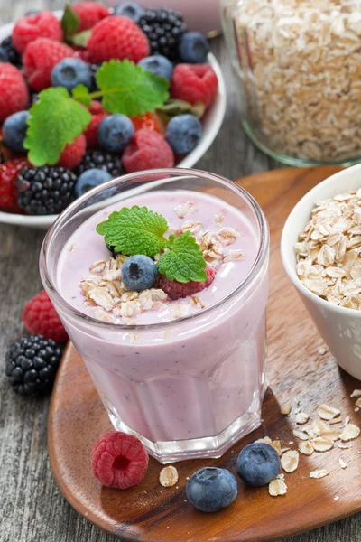 Frullato di bacche con farina d'avena in un bicchiere su tavolo di legno, verticale — Foto Stock