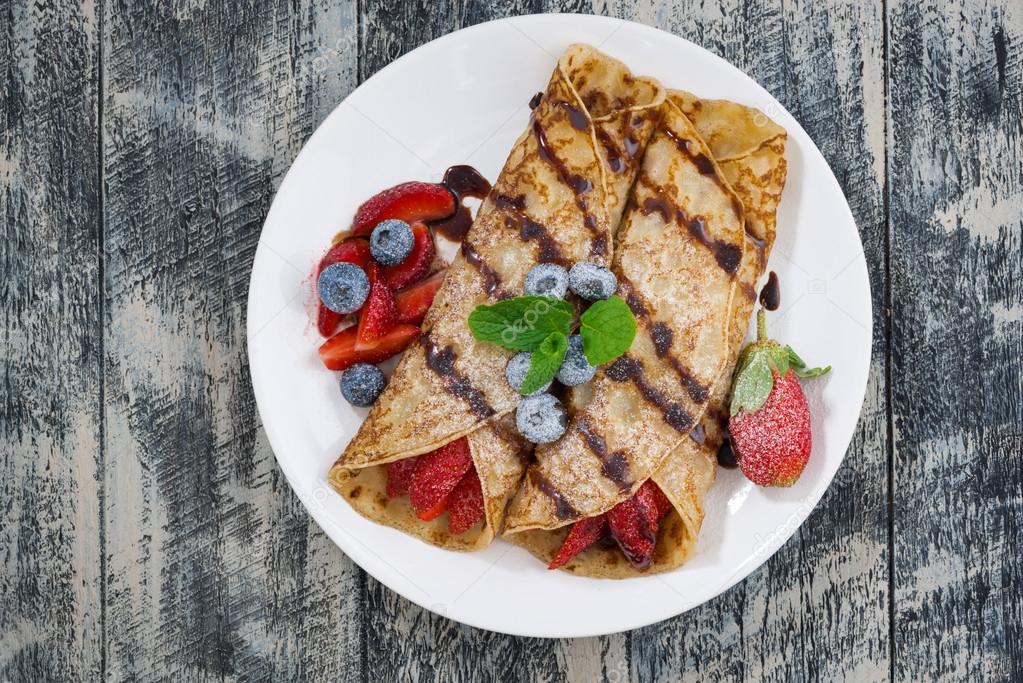 delicious crepes with berries and chocolate sauce, top view