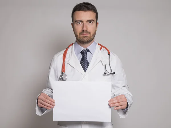 Médico segurando um outdoor copyspace branco isolado em fundo cinza — Fotografia de Stock
