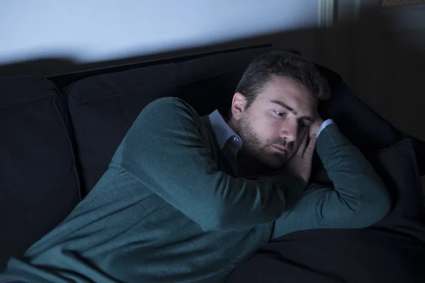 Человек в депрессии, думая лежа на диване — стоковое фото
