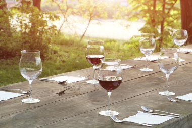 kırsal kesimde açık ahşap bir masa üzerinde şarap bardakları