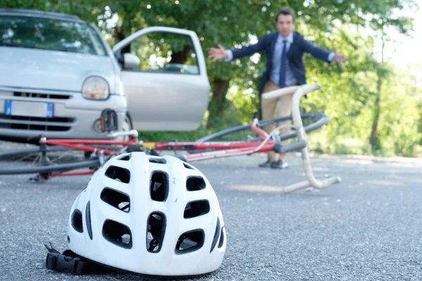Conductor que sale de su coche para ayudar al hombre dolorido después de accidente de bicicleta en el asfalto — Foto de Stock