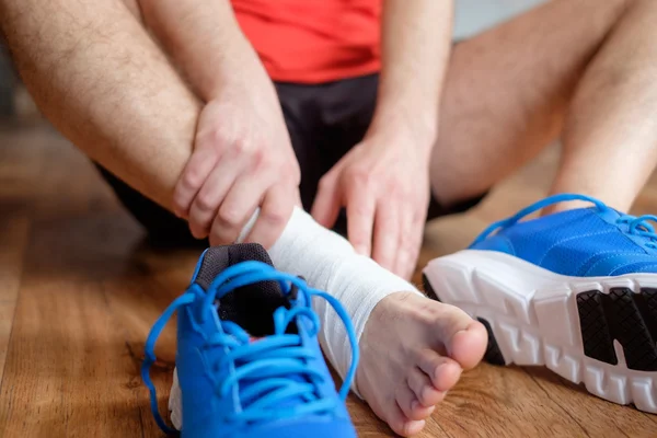 Desportista massagear seu tornozelo ferido após um acidente desportivo — Fotografia de Stock