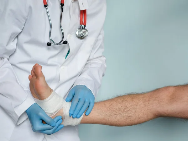 Primer plano del médico vendando un pie lesionado después de un accidente —  Fotos de Stock