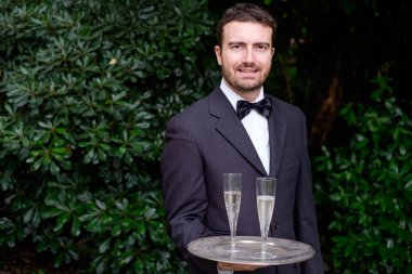 profesyonel garson formasıyla şampanya hizmet vermektedir