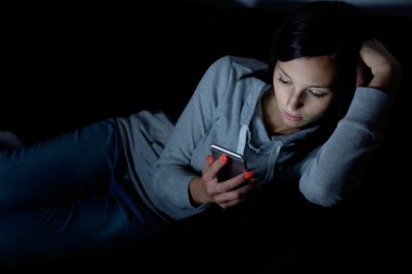 Cep telefonu ekrana bakarak genç kadın portresi