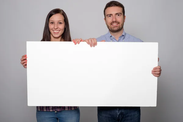 Jóvenes amantes pareja sosteniendo un cartón blanco aislado —  Fotos de Stock