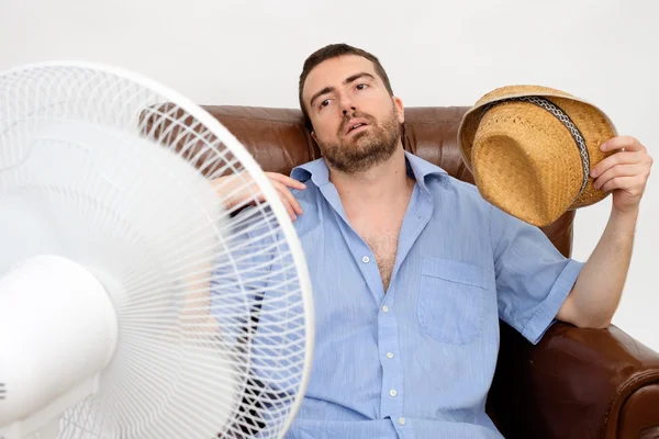 Homem corado sentindo quente na frente de um ventilador — Fotografia de Stock