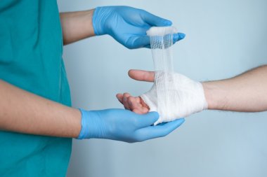 close up of doctor bandaging one hand after an accident clipart