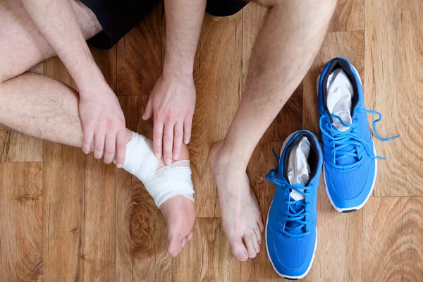 Deportista masajeando su tobillo lesionado después de un accidente deportivo — Foto de Stock