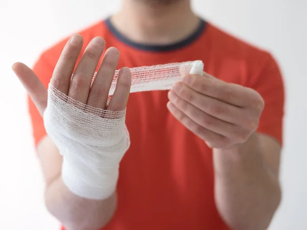 Hombre deportivo con vendajes medicación en la mano que sufre después de una lesión deportiva —  Fotos de Stock