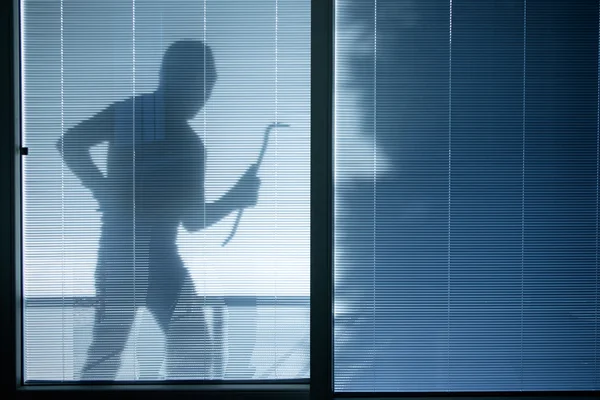 Burglar wearing a balaclava looking through the house window — Stock Photo, Image