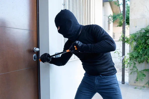 Ladrón tratando de forzar una cerradura de puerta usando una palanca —  Fotos de Stock