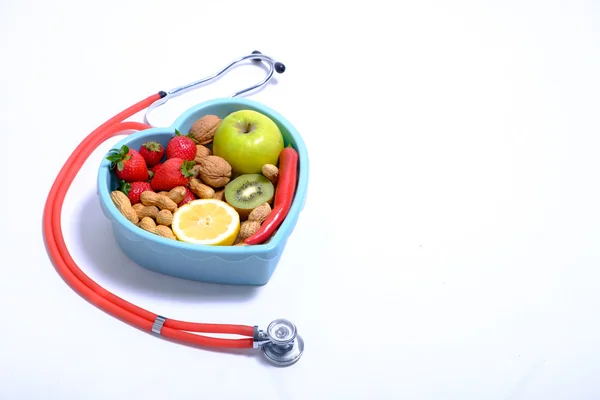Herzförmige Schüssel mit Gemüse und Stethoskop isoliert auf weißem Hintergrund — Stockfoto