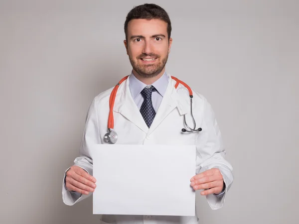 Médico segurando um banner de papelão branco isolado no backgro cinza — Fotografia de Stock
