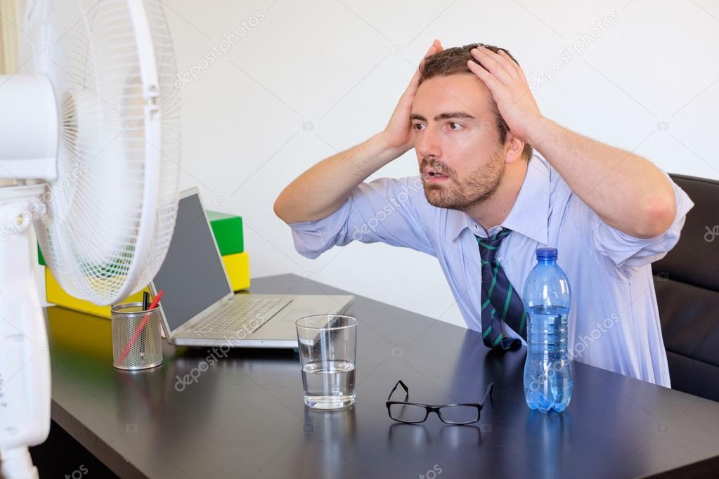 Flushed employee feeling hot in front of a fan Stock Photo by ©tommaso1979 117097590